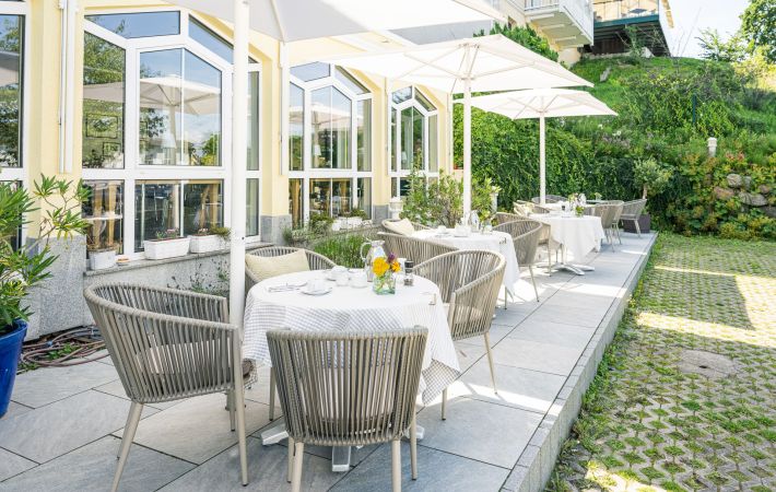 Für das Frühstück eingedeckte Tische auf der Sonnenterrasse des Inselhotels Rügen in Göhren